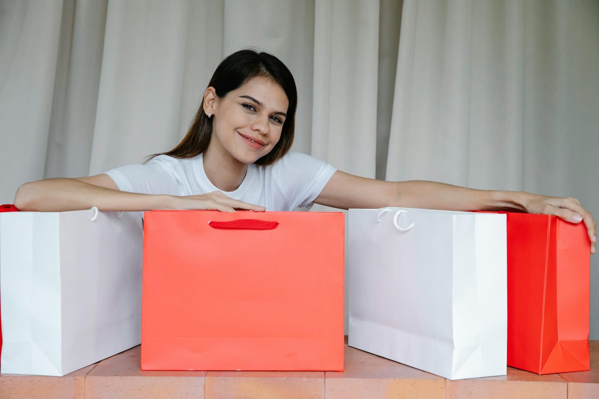 Smiling woman with colorful shopping bags indoors, conveying joy and retail therapy charm.