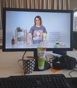 A computer screen displays a woman conducting an efficacy demo video for skincare, with text about testing patches for