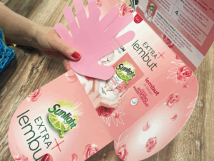 A hand holds an open pink pamphlet with a hand-shaped cutout, using science into demos to showcase Sunlight Extra